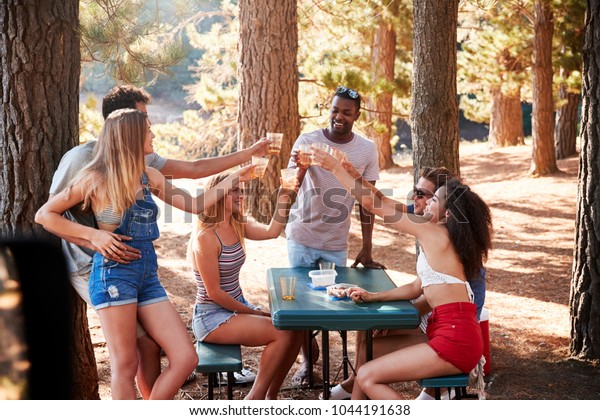 Group of adult friends hanging out by a lake making a toast.