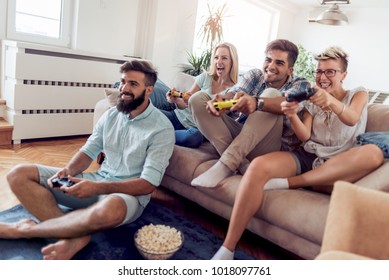 Group Of Adult Friends Sitting In Modern Apartment And Playing Video Games.