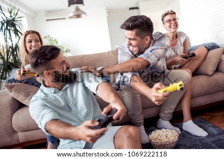 Group of adult friends sitting in modern apartment and playing video games.