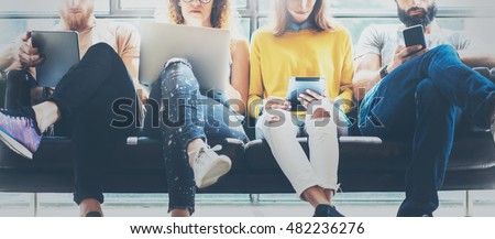 Group Adult Hipsters Friends Sitting Sofa Using Modern Gadgets.Business Startup Friendship Teamwork Concept.Creative People Working Together Sale Project.Coworking Process Office Studio.Blurred Wide