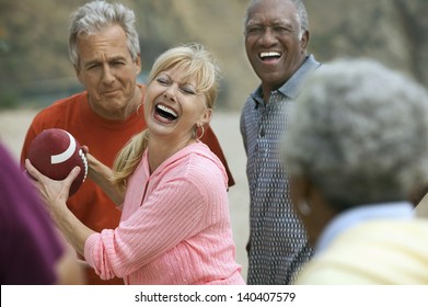 Group of adult multiethnic friends playing American football on the beach - Powered by Shutterstock