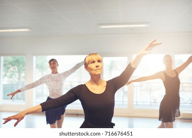 Group Of Adult Women Exercising And Performing Ballet Dance Together In The Class.