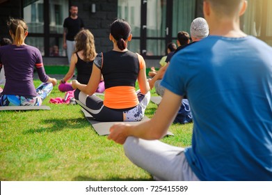 Group Of Adults Attending A Yoga Class Outside In Yard