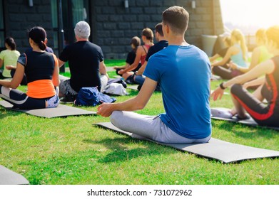 Group Of Adults Attending A Yoga Class Outside In Yard