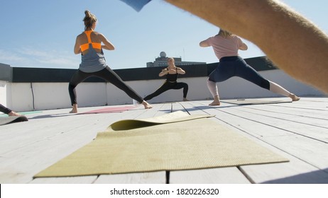 Group Of Adults Peoples Doing Yoga Outdoors On The Roof Of The House. Outdoor Group Yoga Classes Back View. Many People Do Yoga Exercises. Meditation And Wellness Lifestyle Concept