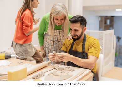 group of adults working in ceramic workshop, multigenerational group of people enjoying their hobby with clay learning in class - Powered by Shutterstock