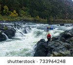 Group of adventure seekers rafting through Rainy Falls, Oregon with spotter watching.