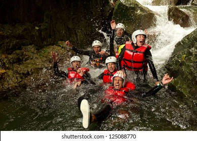 A group of adventurous individuals wearing helmets and using machinery to navigate a dynamic river canyon in Ecuador during a thrilling canyoning expedition.