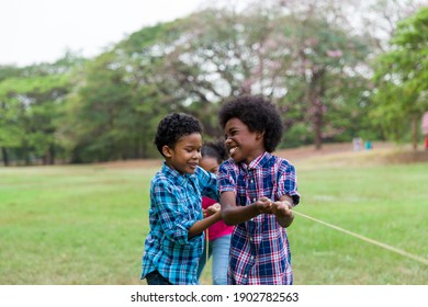 Group of African American boy and girl playing tug of war together in the park. Cheerful children with curly hair having fun with tug of war. Black children people playing tug of war - Powered by Shutterstock