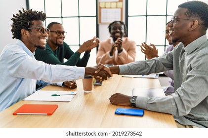 Group of african american business workers smiling and clapping to partners handshake at the office.