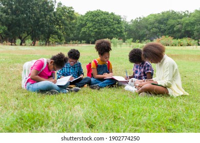 Group Of African American Children Learning And Writing Book In The Park. Diversity Black People Learning Outside The Classroom. Kids Field Trips Outside. Kids And Educational Concept