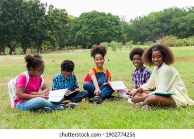 Group of African American children learning and writing book in the park. Diversity black people learning outside the classroom. Kids field trips outside. Kids and educational concept