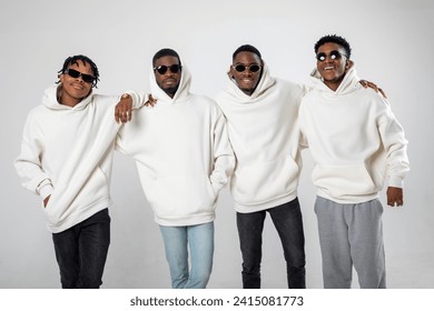 Group of African American guys in brown hoodies posing on a white background wearing sunglasses