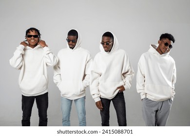 Group of African American guys in brown hoodies posing on a white background wearing sunglasses