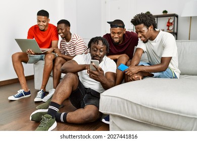 Group Of African American People Smiling Happy Using Smartphone And Laptop At Home.