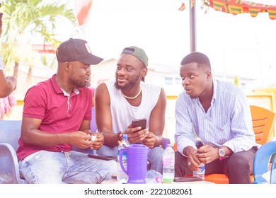 group of african guys having interactions outside, table in front of them, one holding smart phone- communication concept  - Shutterstock ID 2221082061