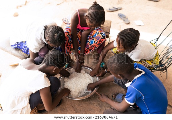 Group of African village children sharing a\
simple rice meal; concept of scarcity of food and malnutrition in\
developing countries