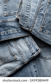 Group of aged denim jeans, arranged as abstract blue textile background, close-up shot