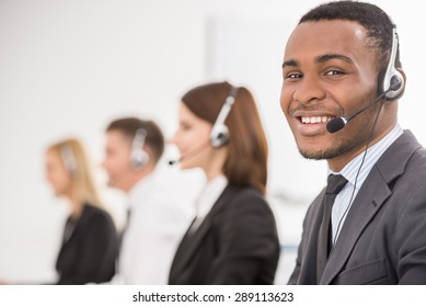 Group Of Agents Sitting In Line In A Bright Call Centre.