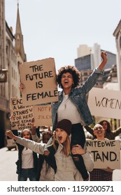 Group Of Aggressive Protesters Marching On The Road With Signboards. Women Holding Protest Signs For Female Future And Empowerment.