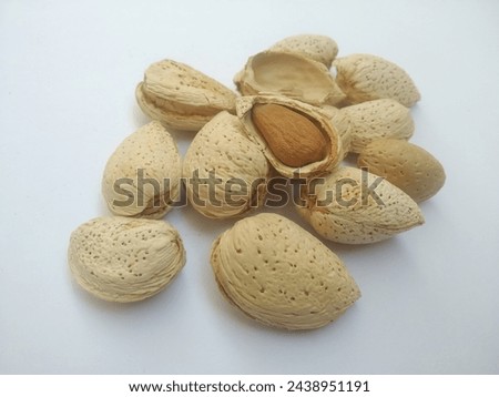 A group of Almonds in shell and one is pealed and visible in brown is our main character of this dry fruit in white background. Full of fat and nutrition.