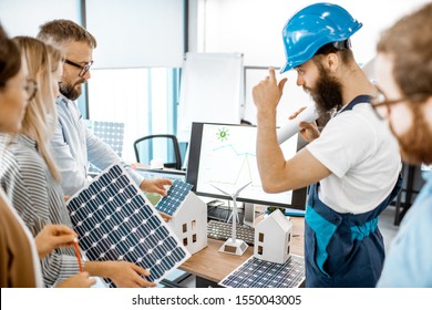 Group Of Alternative Energy Engineers Discussing A Project With A Worker During A Meeting In The Office. Green Energy Development Concept
