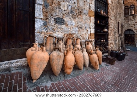 A group of amphorae.  An amphora (English plural: amphorae or amphoras) is a type of container with pointed bottom which fit tightly against each other in storage for delivery by land or sea.
