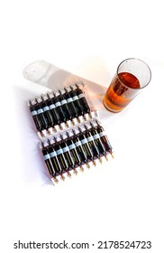 Group Of Ampoules With A Transparent Medicine In Medical Laboratory. Horizontal Perspective View Of Many Brown Ampoules Set In Pharmaceutical Packaging White Container