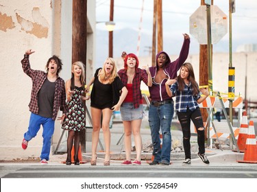 A group of angry punk rock teens shout loudly across the street towards the camera.