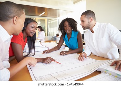 Group Of Architects Discussing Plans In Modern Office