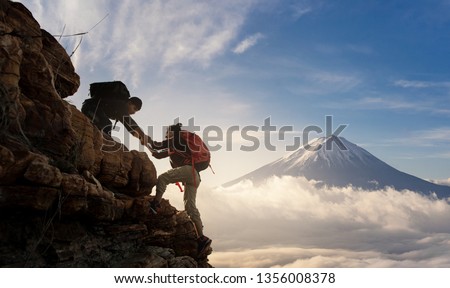 Group of Asia hiking help each other silhouette in mountains with sunlight.
