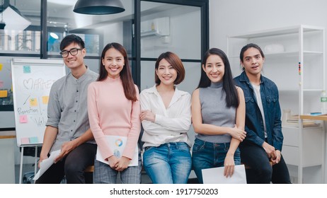 Group Of Asia Young Creative People In Smart Casual Wear Looking At Camera And Smiling In Creative Office Workplace. Diverse Asian Male And Female Stand Together At Startup. Coworker Teamwork Concept.