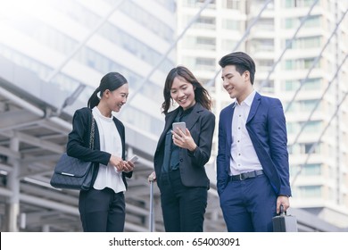 Group Of Asian Business Colleagues Using Mobile Phone's Outside The Office.