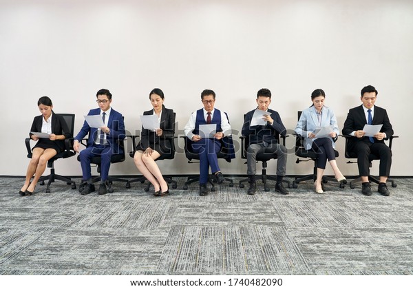 group of asian business people men and women\
waiting in line for job\
interview