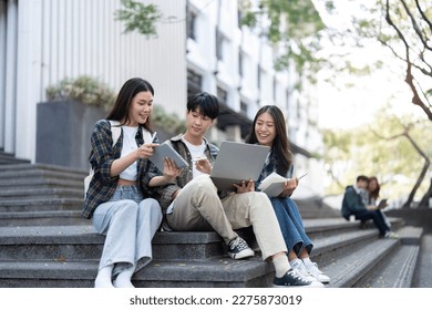 Group of Asian college student reading books and tutoring special class for exam on grass field at outdoors. Happiness and Education learning concept. Back to school concept. Teen and people theme.