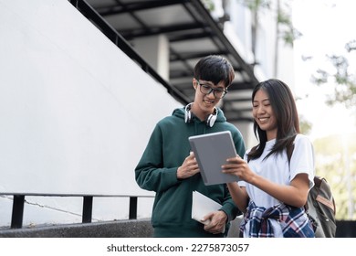 Group of Asian college student reading books and tutoring special class for exam on grass field at outdoors. Happiness and Education learning concept. Back to school concept. Teen and people theme.