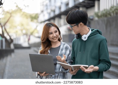 Group of Asian college student reading books and tutoring special class for exam on grass field at outdoors. Happiness and Education learning concept. Back to school concept. Teen and people theme.