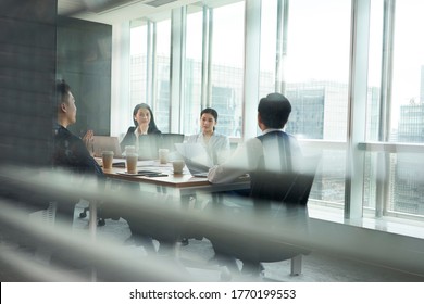 Group Of Asian Corporate Executives Meeting In Conference Room In Office