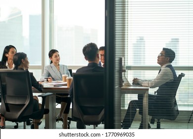 Group Of Asian Corporate Executives Meeting In Conference Room In Office