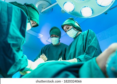 Group Of Asian Doctor And Nurse Surgeons In Hospital Operating Theater. Medical Team Performing Surgery In Operation Room.Medical Team Doing Critical Operation.health And Wellness Concept