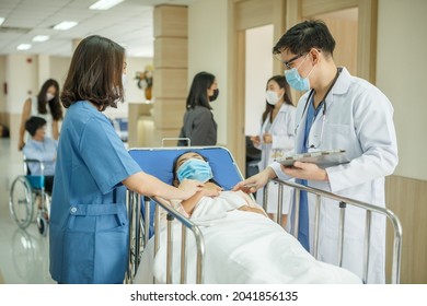 group of asian doctor and nurse wearing surgical face mask carrying patient on hospital gurney in hospital . new normal during  Coronavirus pandemic or Covid-19 outbreak - Powered by Shutterstock