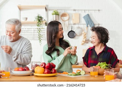 Group of asian elder senior friends at dinner party at home, senior friend preparing salad and fruit juice with her daughter with smiling cheerful moment conversation with elder friend laugh smile - Powered by Shutterstock