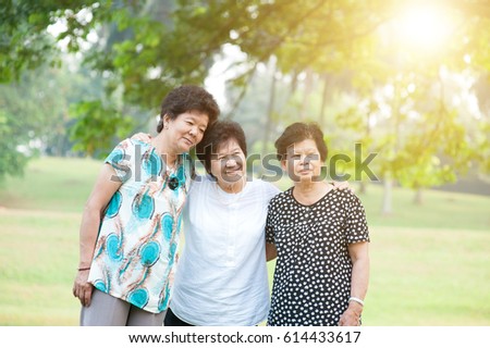 Group of Asian elderly women having fun at green park, active senior adult outdoors, friendship concept, morning sun flare background.