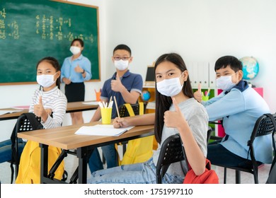 Group Of Asian Elementary School Students And Teacher Wearing Hygienic Mask To Prevent The Outbreak Of Covid 19 In Classroom While Back To School Reopen Their School, New Normal For Education Concept.