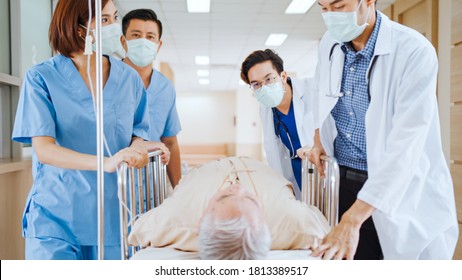 Group Of Asian Emergency Doctor And Nurse Team Wear Face Mask, Push Emergency Stretcher, Transport Senior Patient In Hospital. Health Care Paramedic Service, Or Medical Rescue Team Operation Concept