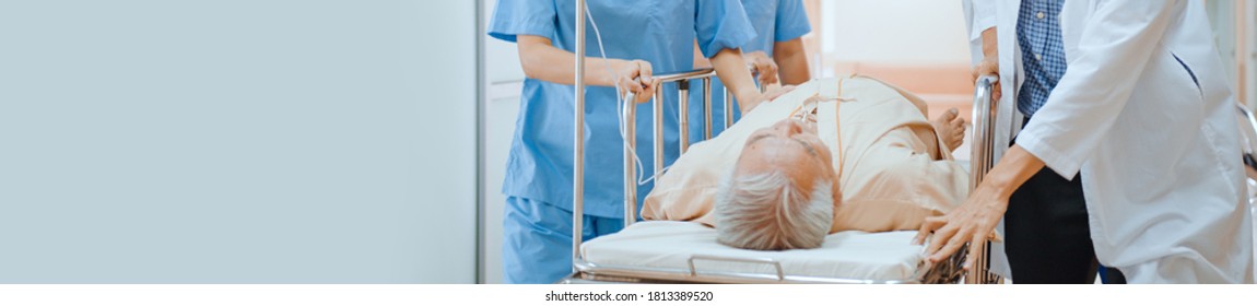 Group Of Asian Emergency Doctor And Nurse Team Push Emergency Stretcher, Transport Senior Patient In Hospital. Health Care Paramedic Service Or Medical Rescue Operation Concept. Banner With Copy Space