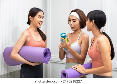 Group of Asian female friends talking together after exercise in yoga class sport club on hydration and vitamin drink supplement post workout for healthy and fitness lifestyle - Powered by Shutterstock