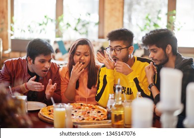 Group Of Asian Friends Eating Pizza During Party At Pizzeria. Happy Indian People Having Fun Together, Eating Italian Food And Sitting On Couch. Shocked And Surprise Faces.