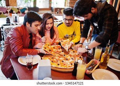 Group Of Asian Friends Eating Pizza During Party At Pizzeria. Happy Indian People Having Fun Together, Eating Italian Food And Sitting On Couch.