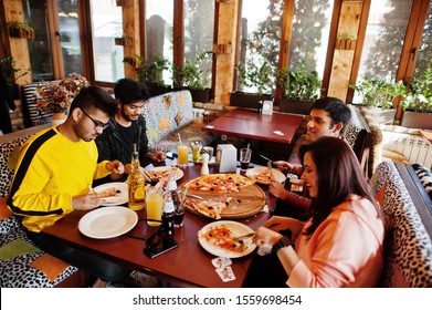 Group Of Asian Friends Eating Pizza During Party At Pizzeria. Happy Indian People Having Fun Together, Eating Italian Food And Sitting On Couch.